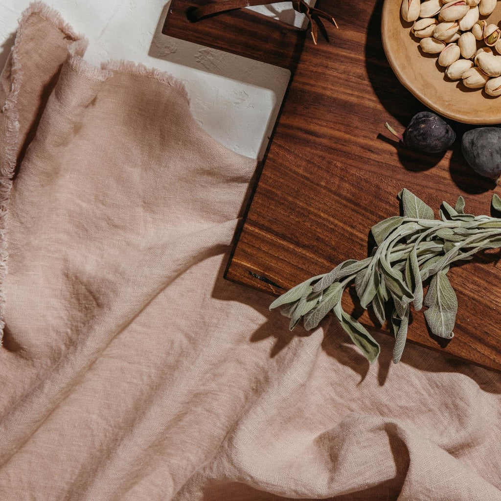 linen table throw with wooden serving board with figs pistachios and sage