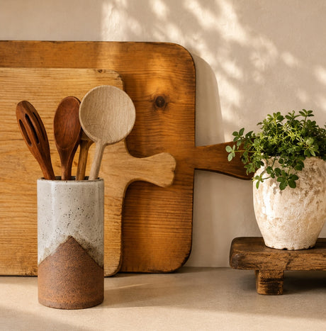 Tall Topanga Ceramic Utensil Crock holding wooden utensils in front of wood cutting boards on a sunlit counter.