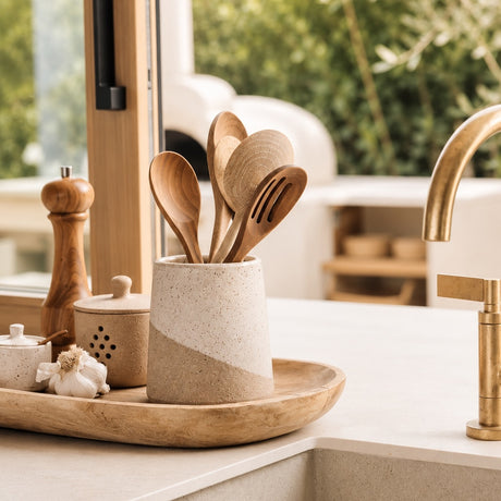 Wide Topanga Ceramic Utensil Crock holding wooden utensils on a tray beside a kitchen sink.