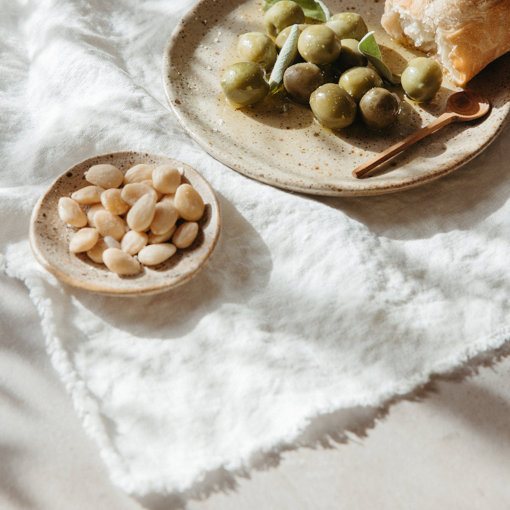linen table throw with stoneware salad plates with olives marcona almonds and bread