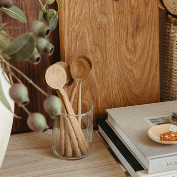 small wooden spoons next to wooden serving board and cookbooks