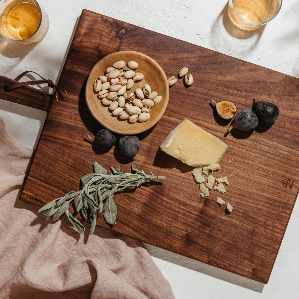 wooden serving board with cheese figs sage and pistachios