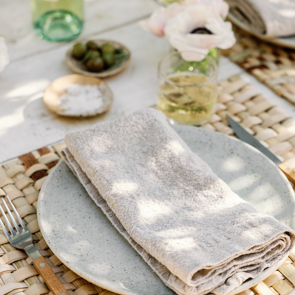 large oversized linen napkins on woven placemat and stoneware dinner plate with recycled glass and Sabre flatware